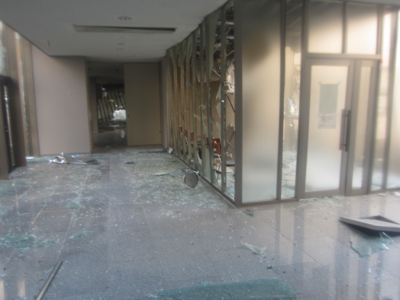 事務本館入口の写真。ガラスが粉々になって散乱している