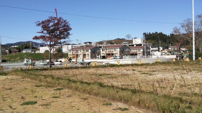 茶色い屋根の3棟の建物の裏には、1Fが浸水した高田小学校が見えます。