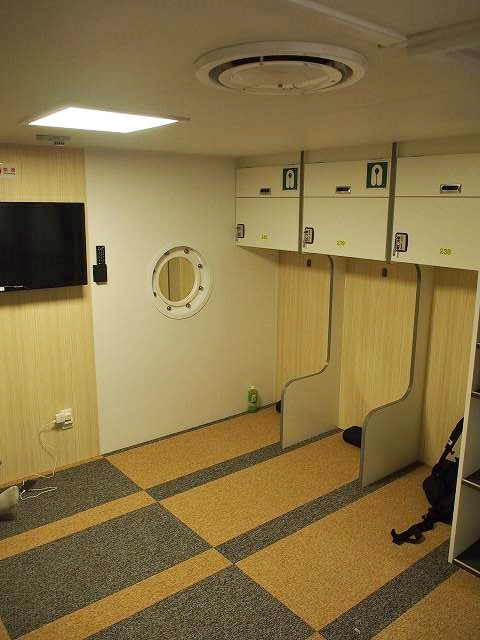 2等和室。スペースが指定されており、顔付近には小さいながらも仕切りがある。頭上の棚はコインロッカーになっている