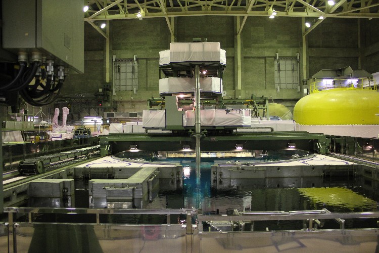 参考：「福島第二原子力発電所1号機　燃料移動作業の完了について | 東京電力 平成26年7月11日」より。手前が使用済み燃料プール。燃料取扱機の金属製のロッドが下ろされているのが、水で満たされた原子炉ウェル。その下に蓋が開けられた圧力容器がある。右の黄色いドーム状は取り外された原子炉の蓋。使用済み燃料は空気中では猛烈な放射線を発するため、その取り出しは燃料プールと圧力容器を水で満たした上、水中で放射線を遮断して行われる