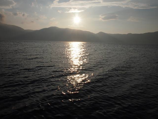 夕暮れ時。太陽の光を反射して湖面は黄金色に輝く。その光は一本の道のように見える。