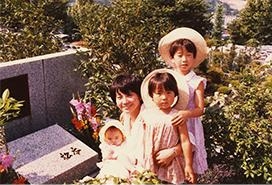 おばあ様の墓前で生後間もない春野さんを抱っこするお母様とお姉様たち。